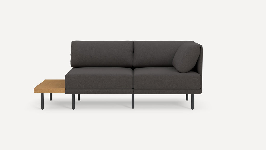 Modern dark gray sectional sofa with metal legs and an attached light wood side table on the left side.