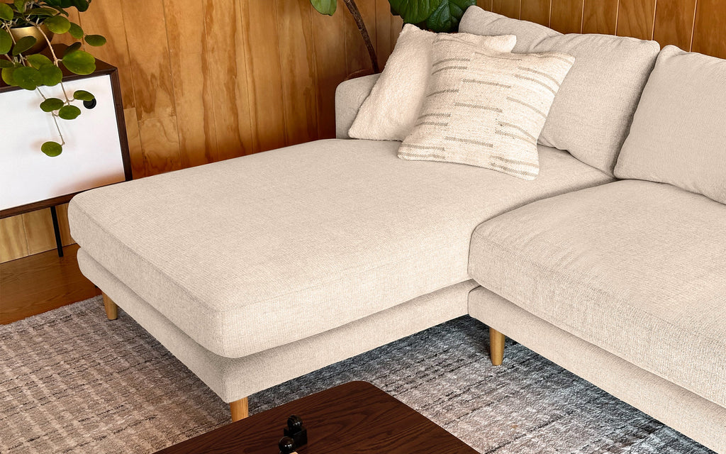 a beige sectional sofa with pillows and pillows on it