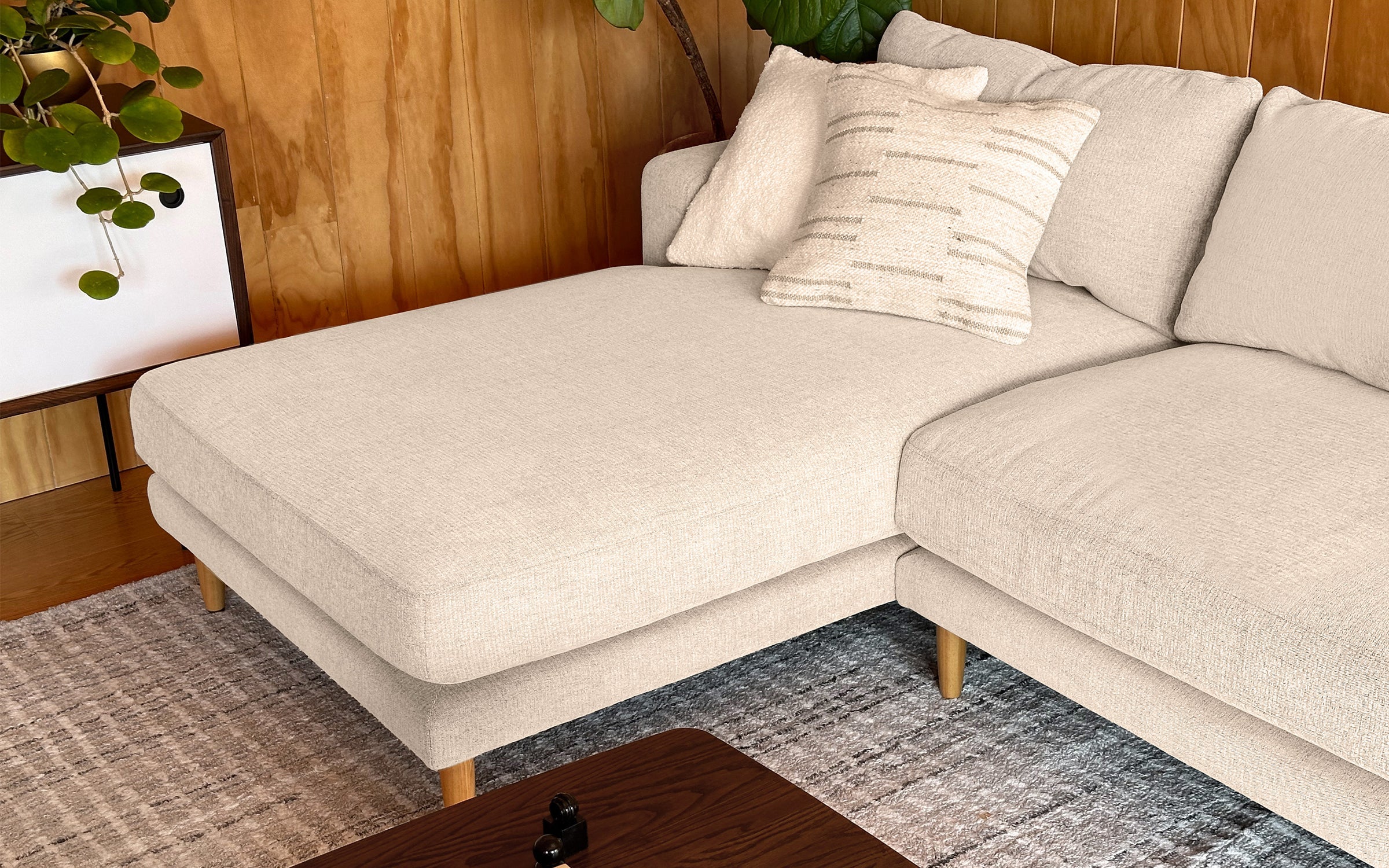 a beige sectional sofa with pillows and pillows on it