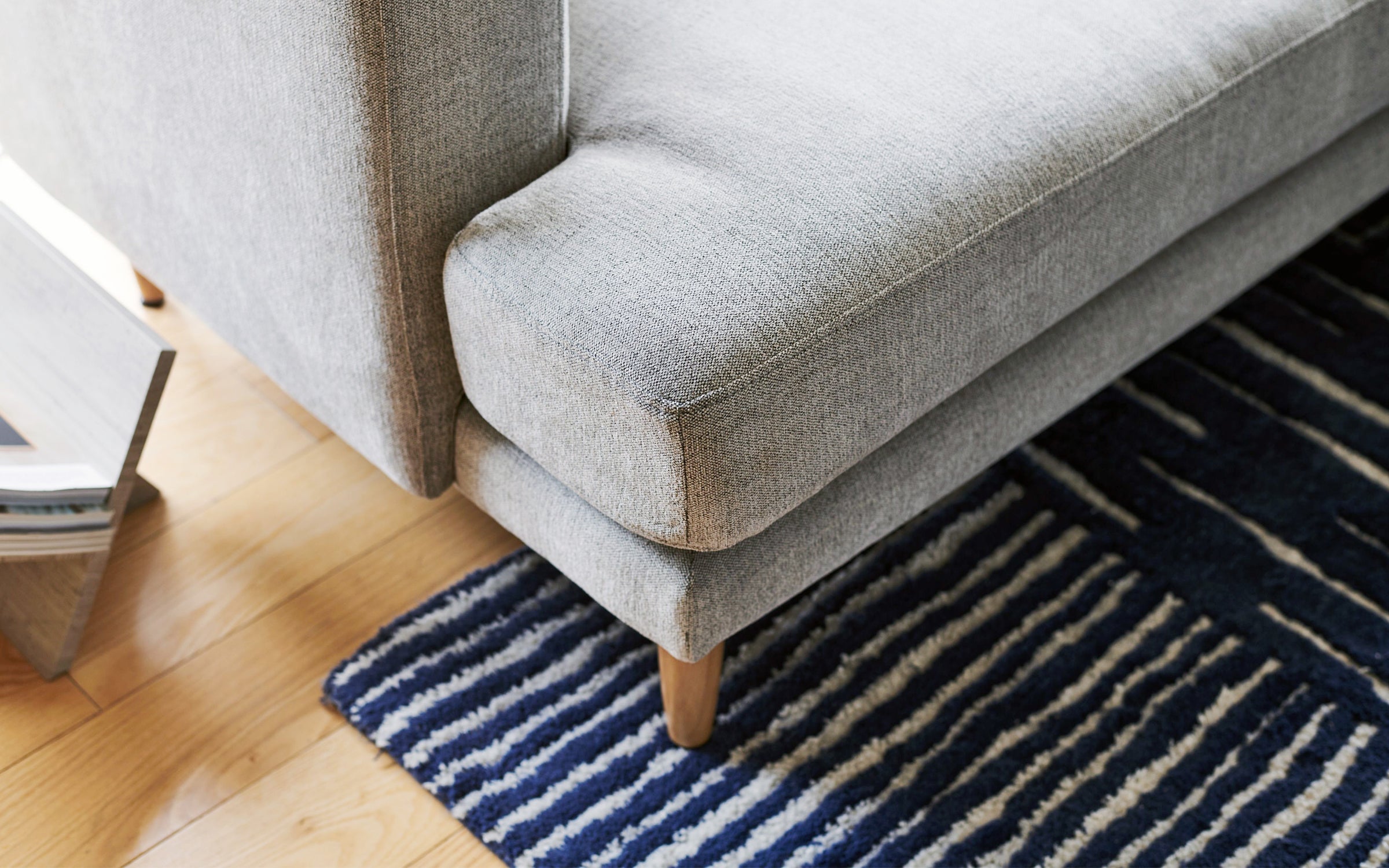 a modern gray sofa with blue and white striped rug