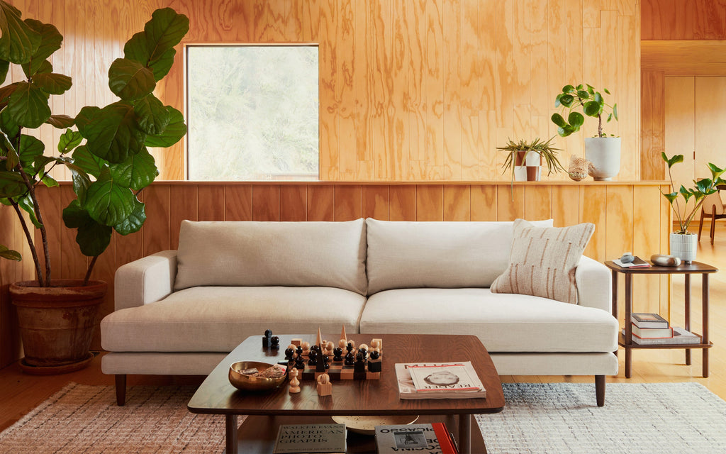 a living room with a large white couch and wooden walls