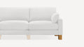 Partial view of a white upholstered loveseat with a matching round pillow on the right armrest and wooden legs.