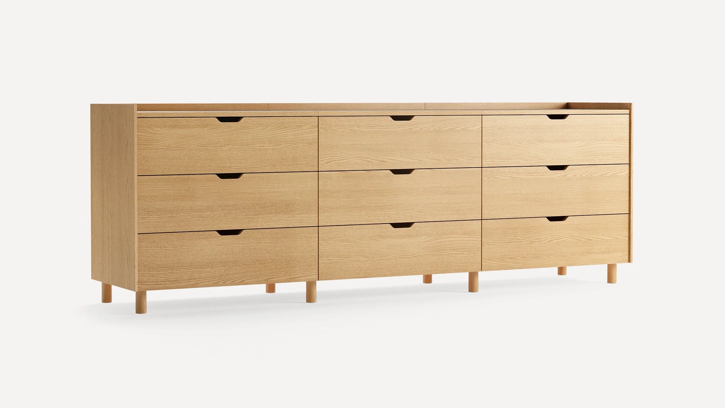 A long, light wood dresser with nine spacious drawers, recessed handles, and six short cylindrical legs, set against a plain white background.
