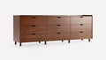 Modern wooden dresser with nine drawers, simple rectangular design, warm brown finish, and short cylindrical legs.