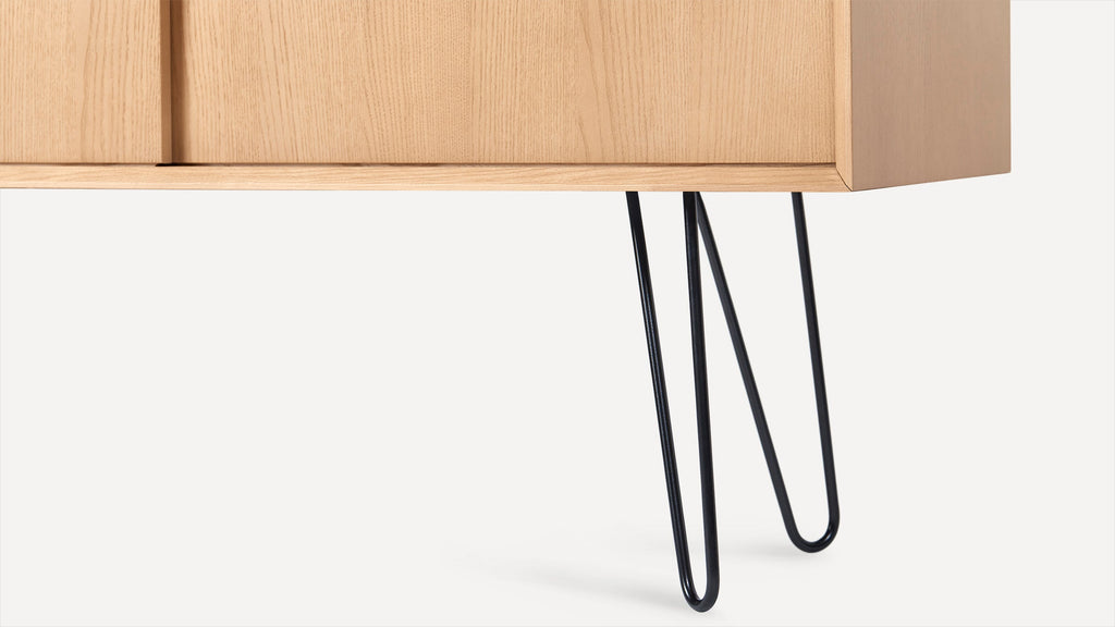 a wooden cabinet with black hairpins on top