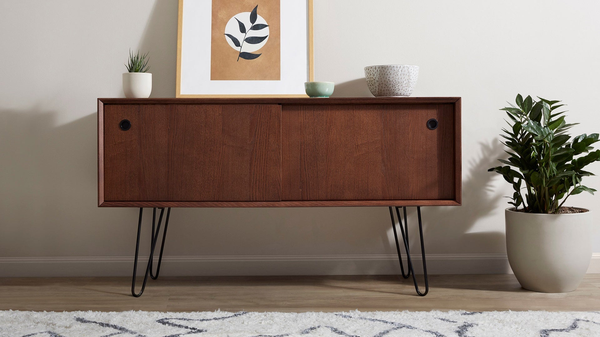 a modern wooden sideboard with black hairpinns and a plant on top