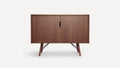 Mid-century modern wooden cabinet with two doors, black central handles, and angled legs with metal supports, in a brown finish.