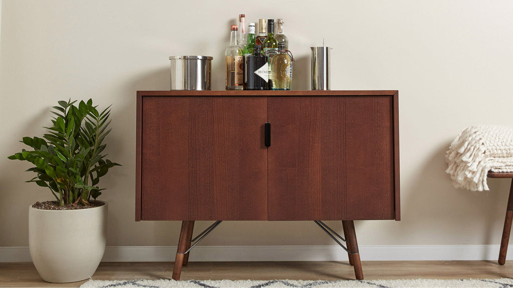 a wooden cabinet with a plant and a bottle of alcohol on top