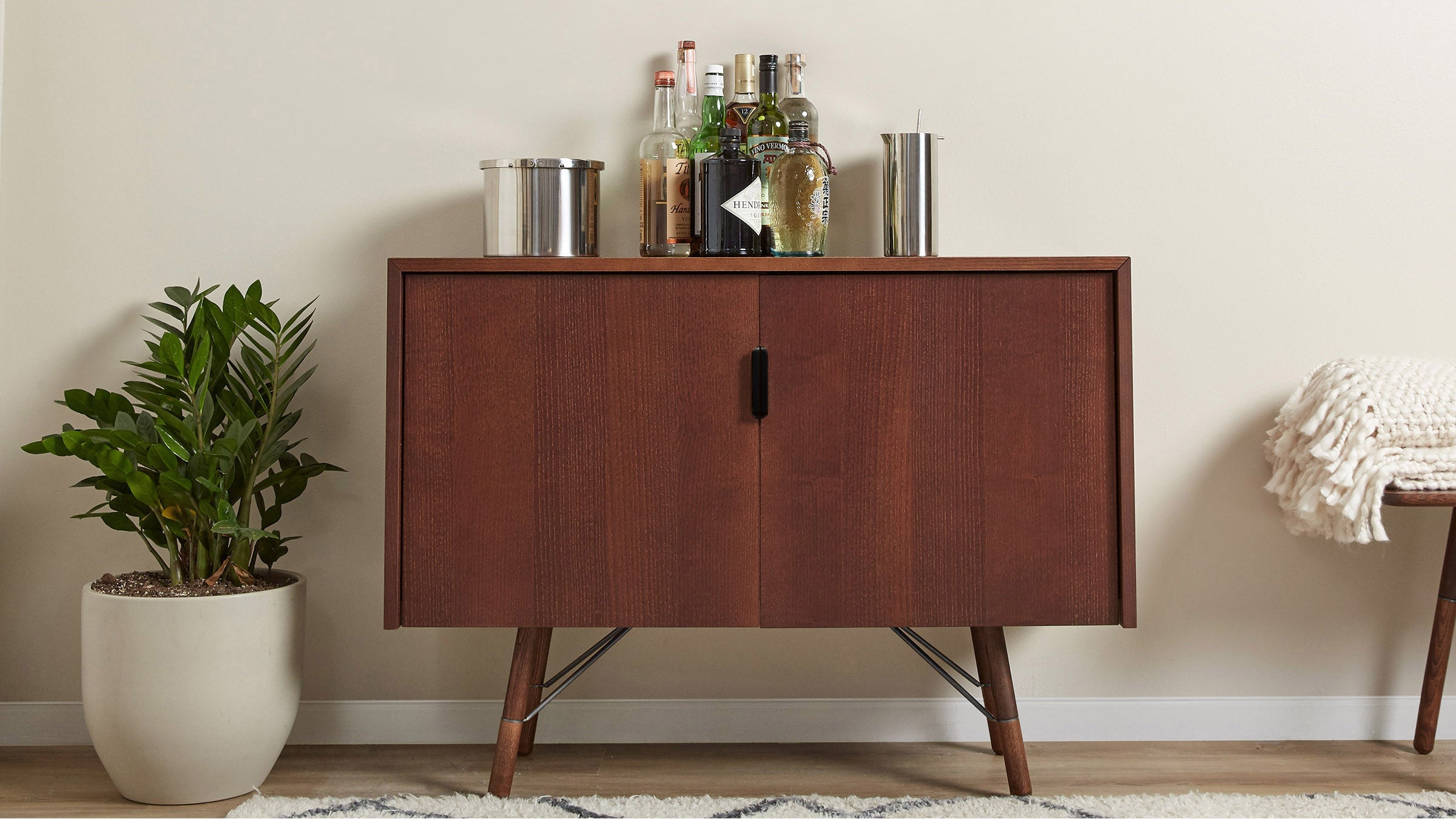 a wooden cabinet with a plant and a bottle of alcohol on top