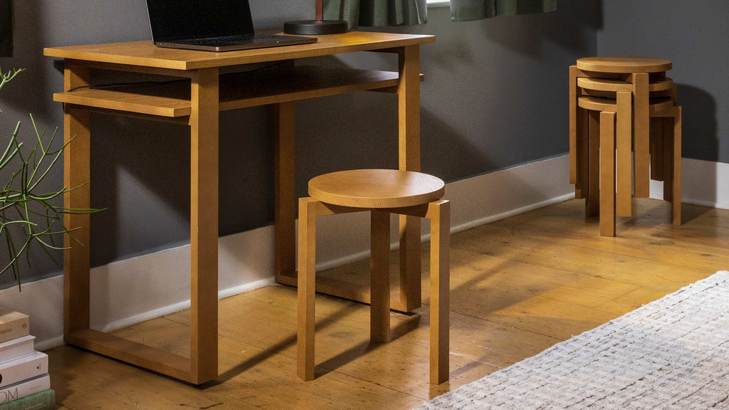 a wooden desk with a laptop and stools
