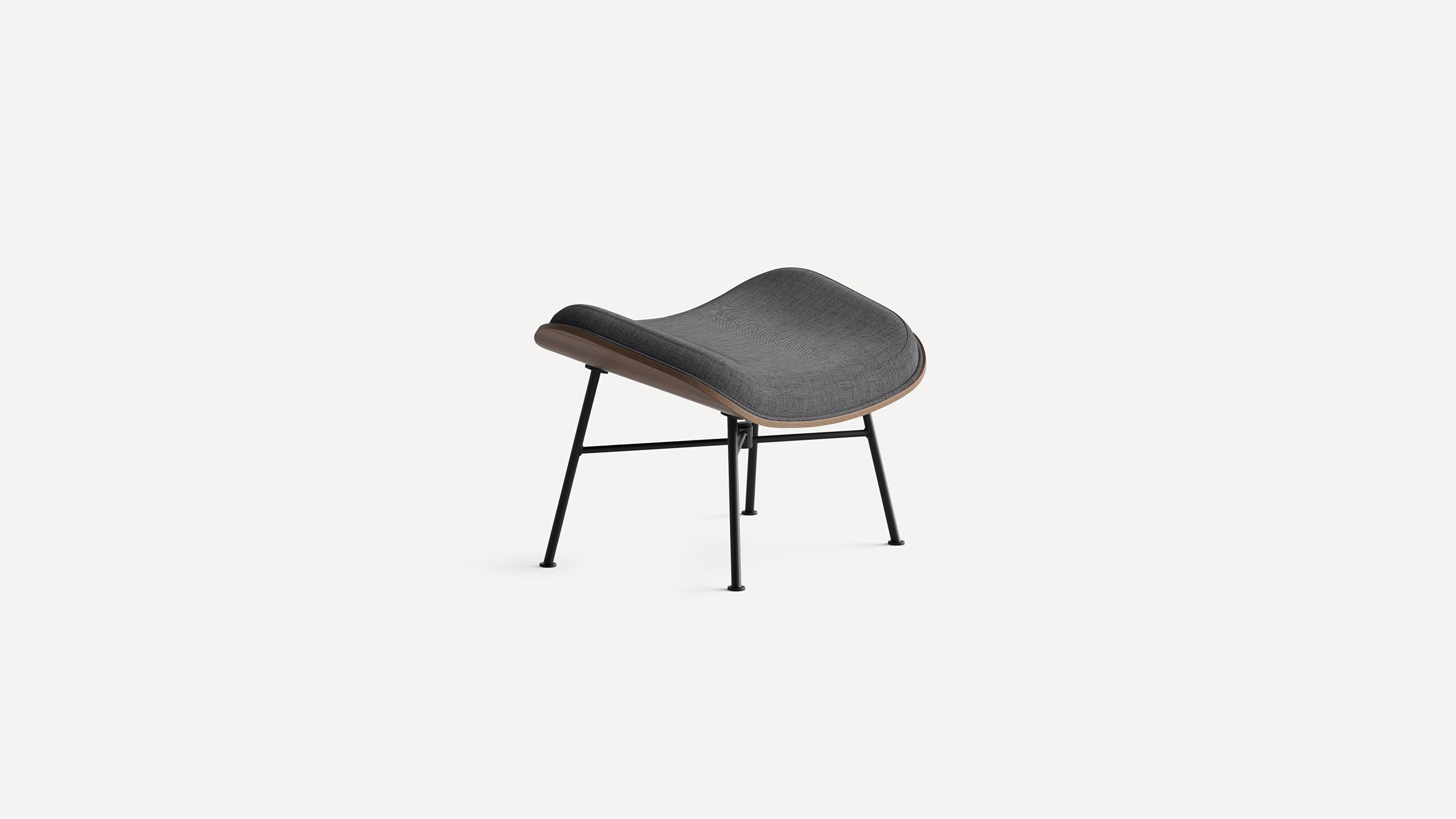 Modern dark gray fabric cushioned ottoman with curved wooden frame and black metal legs on white background.