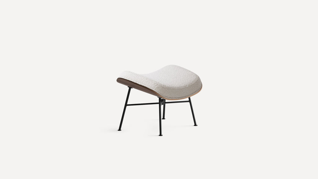 Modern ottoman with curved white cushioned top, wooden base edge, and black metal legs on a white background.