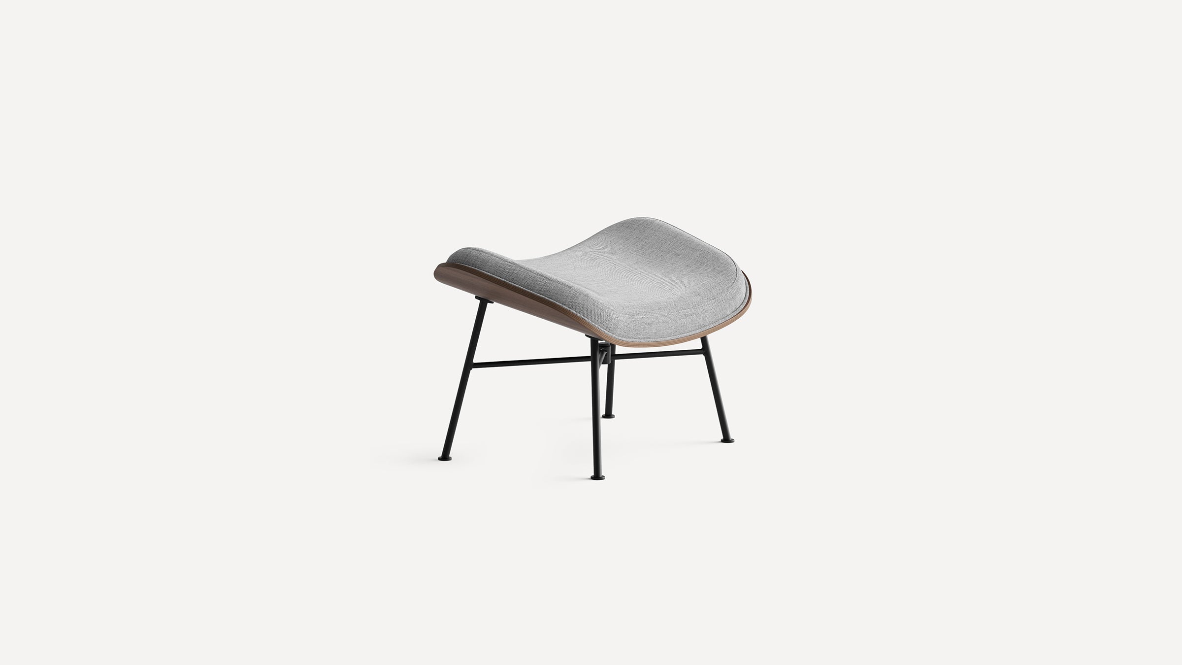 Modern ottoman with curved grey fabric cushion, walnut wood frame, and black metal legs, isolated on white background.
