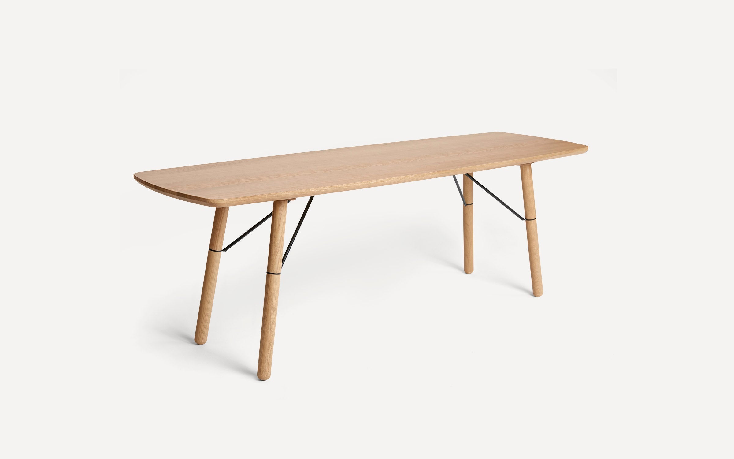 Rectangular wooden dining table with rounded edges, four angled legs, and black metal supports on a white background.