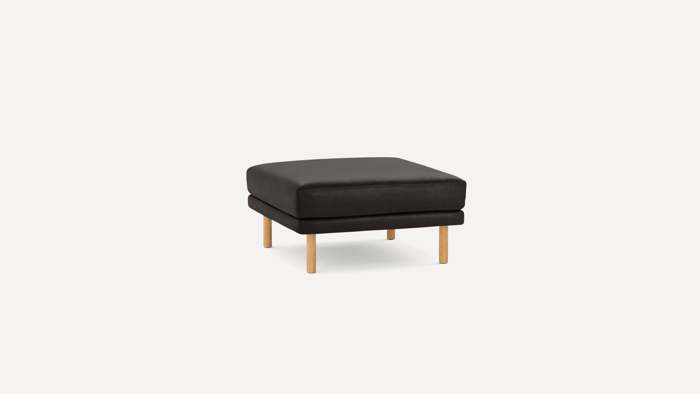 Square black leather ottoman with wooden legs, minimalist and modern design, suitable for living room seating or footrest.