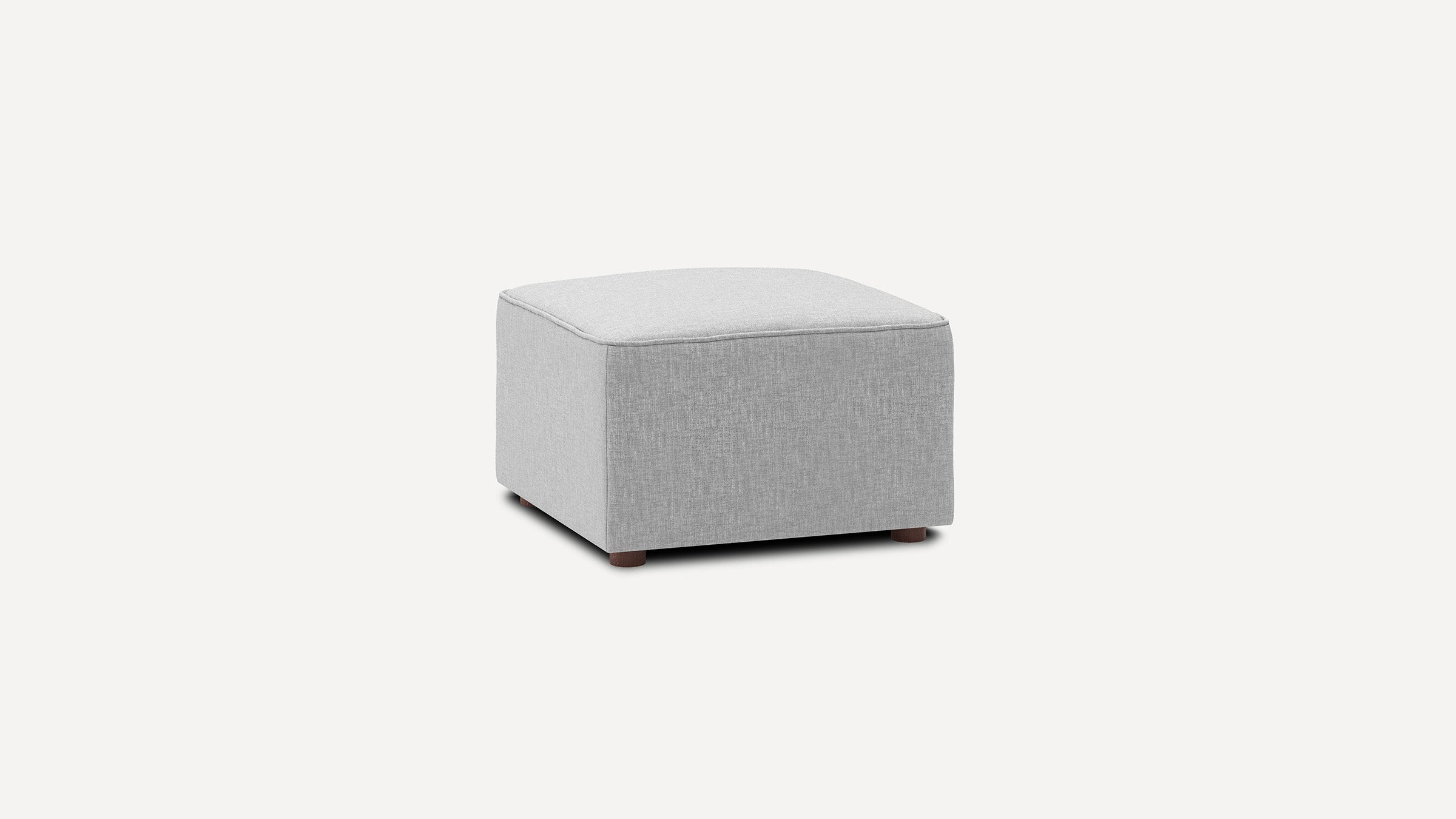 Light grey fabric ottoman with a square shape, cushioned top, and short wooden legs on a plain background.
