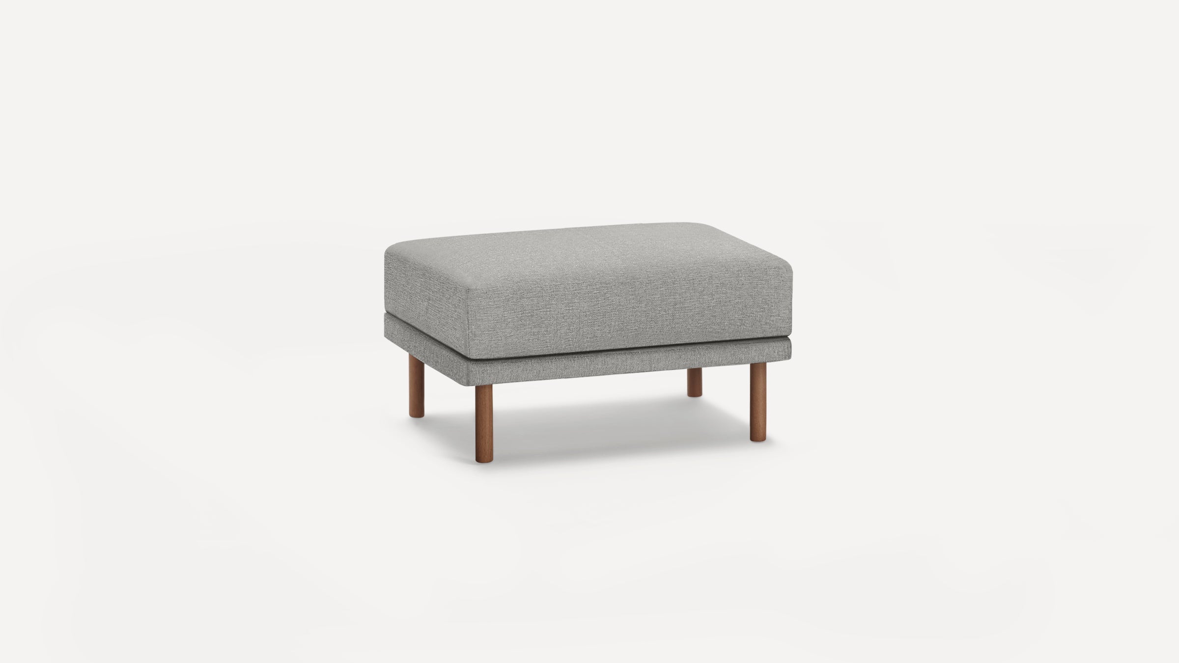 Rectangular light gray fabric ottoman with four cylindrical wooden legs, minimalist and modern design.