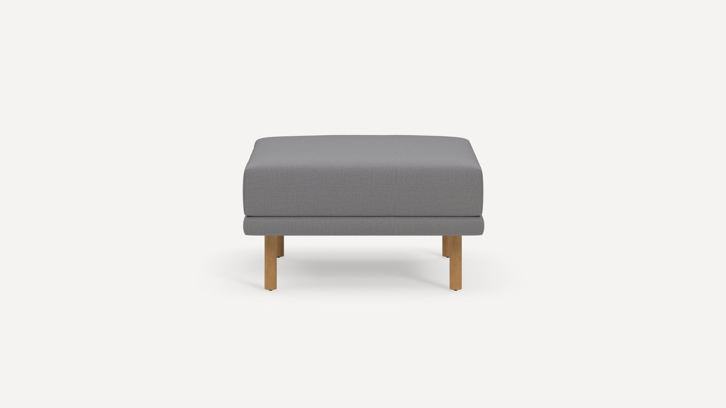 Modern gray upholstered ottoman with clean lines and wooden legs, shown against a plain white background.