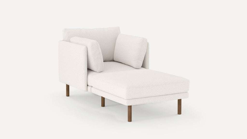 Modern white chaise lounge with plush cushions and wooden legs, featuring a textured fabric upholstery.
