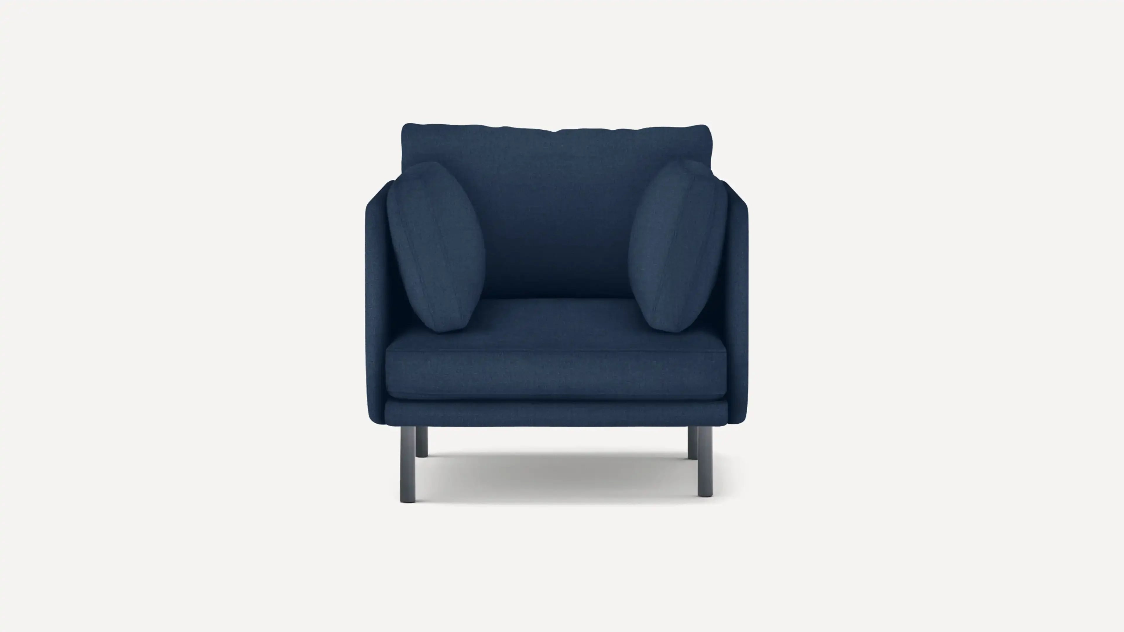 Modern deep blue upholstered armchair with cushioned seat, backrest, and matching side pillows, supported by four metal legs.
