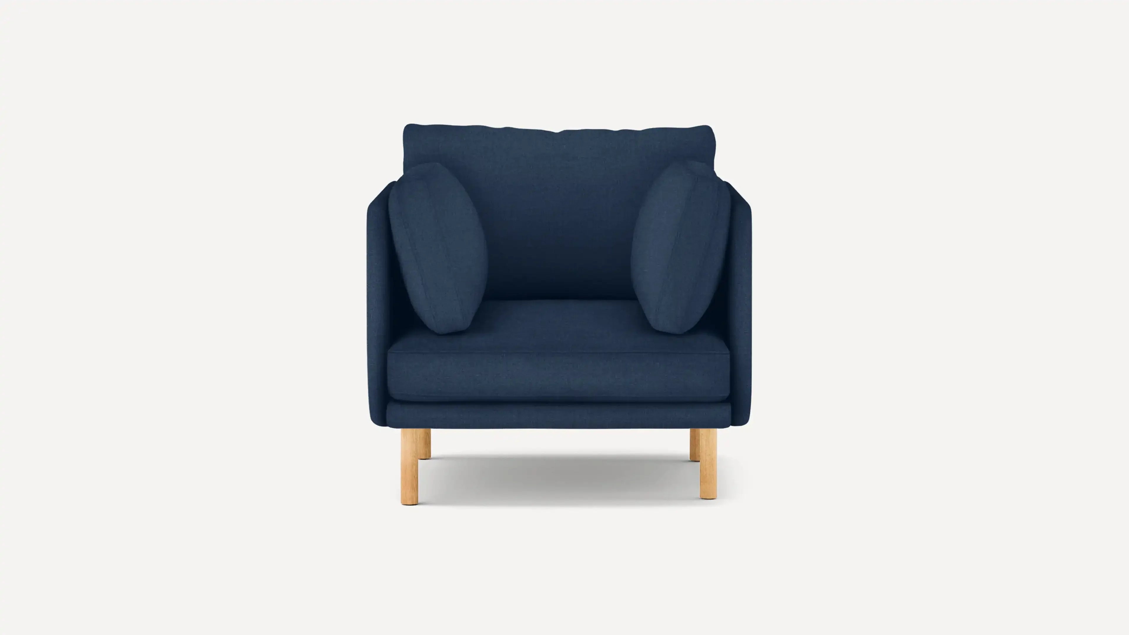 Front view of a modern navy blue armchair with two cylindrical cushions and wooden legs on a white background.