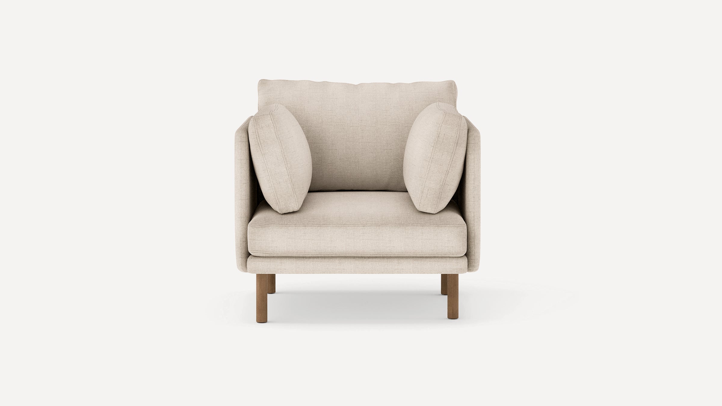 Beige upholstered armchair with two side pillows, thick seat cushion, and wooden legs on a plain white background.