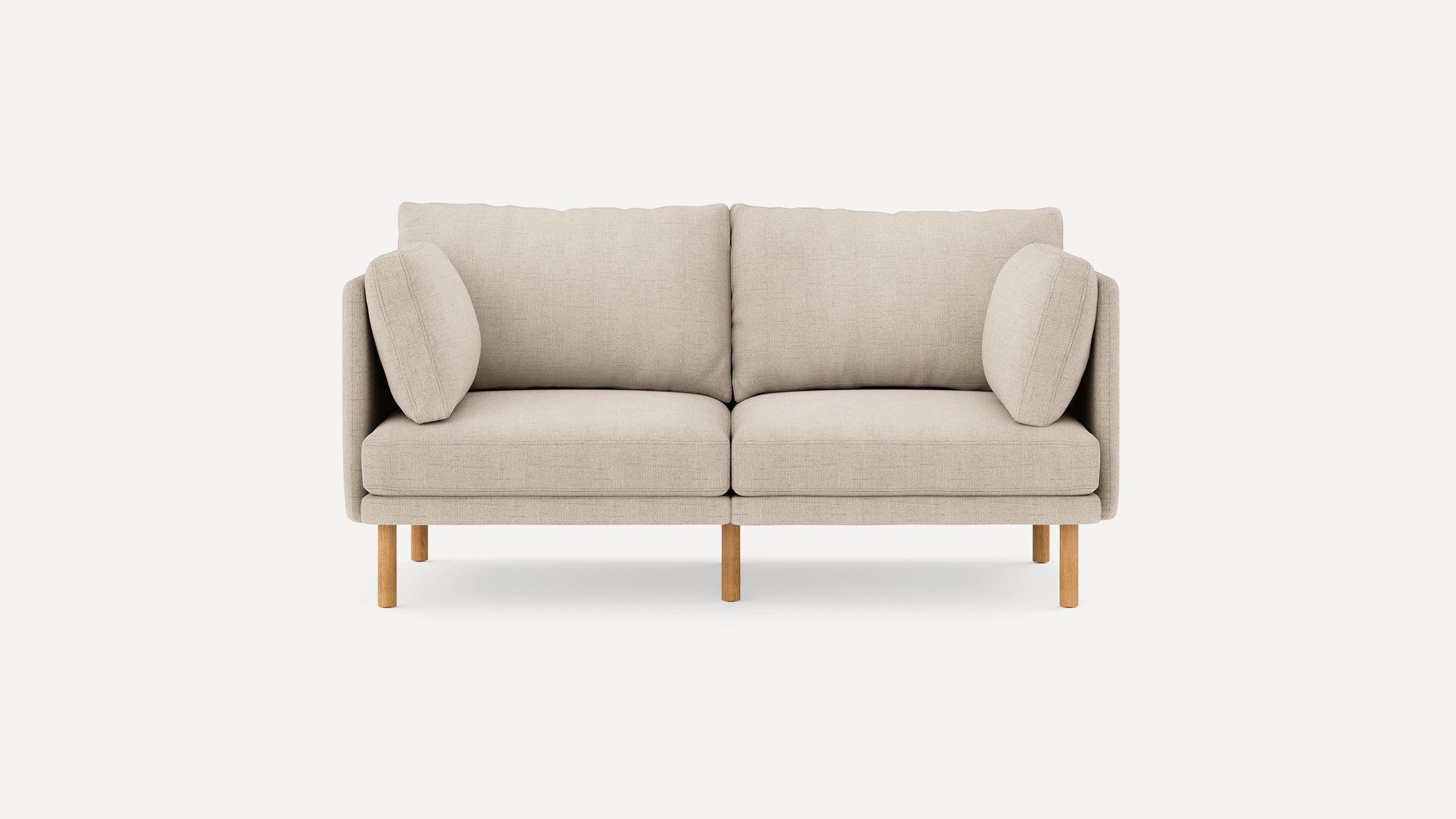 Beige two-seater sofa with wooden legs, cushioned backrest and armrest pillows, displayed on a plain white background.