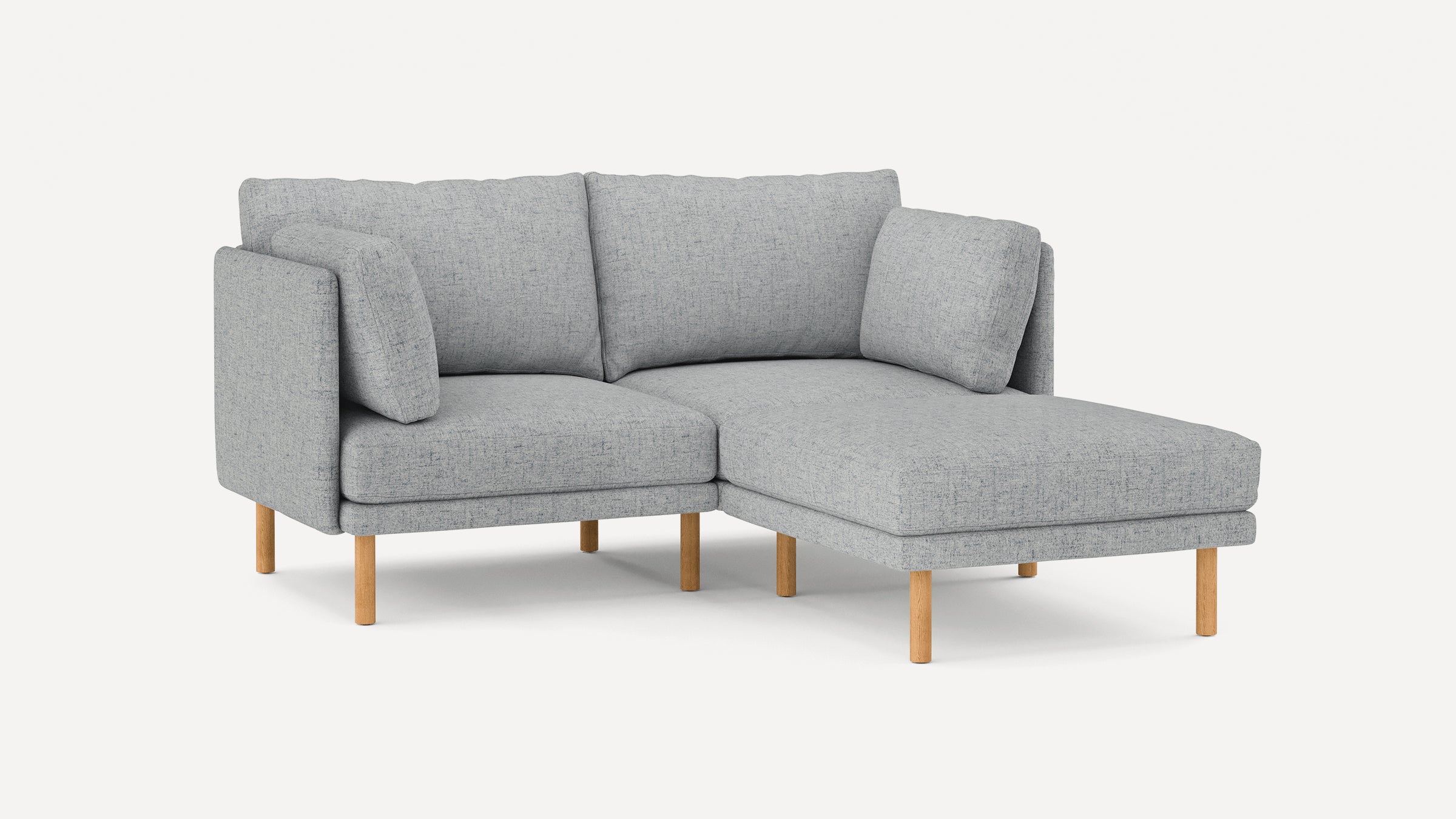 Light gray fabric sectional sofa with wooden legs, featuring a chaise lounge on the right side and plush cushions.