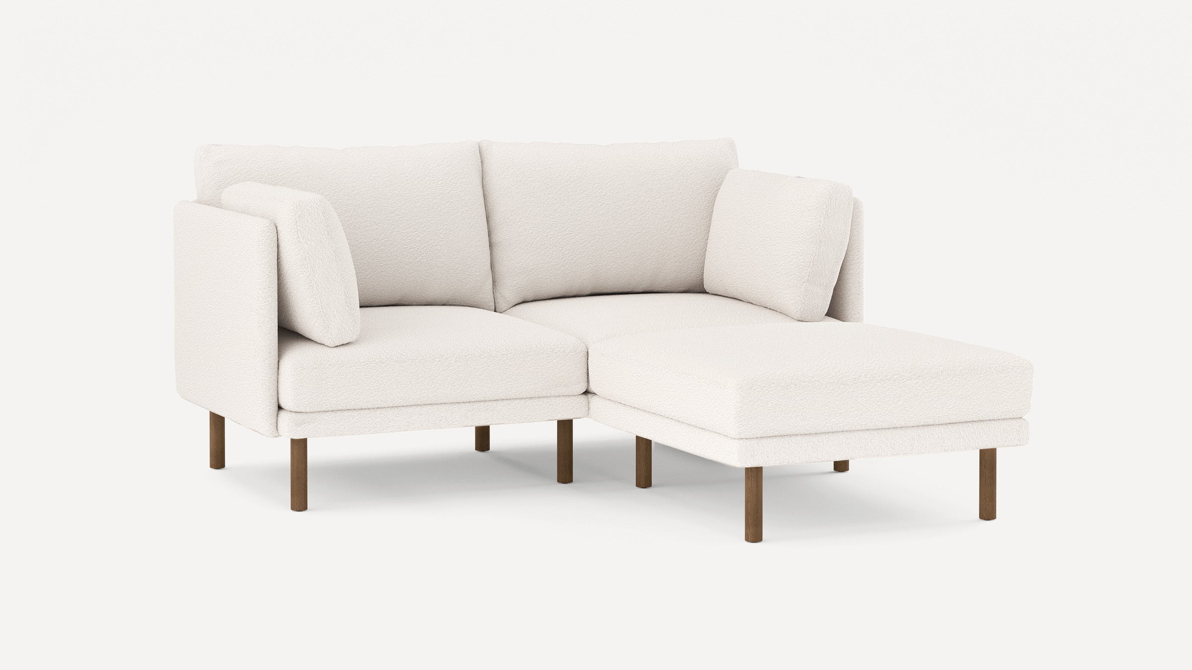 Modern white sectional sofa with textured fabric, wooden legs, and cushioned seats, featuring a chaise lounge on the right side.