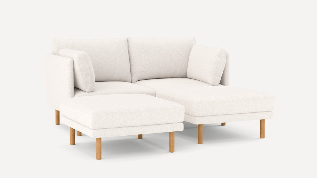Modern white sectional sofa with wooden legs, plush cushions, and a left-facing chaise lounge, minimalistic design.
