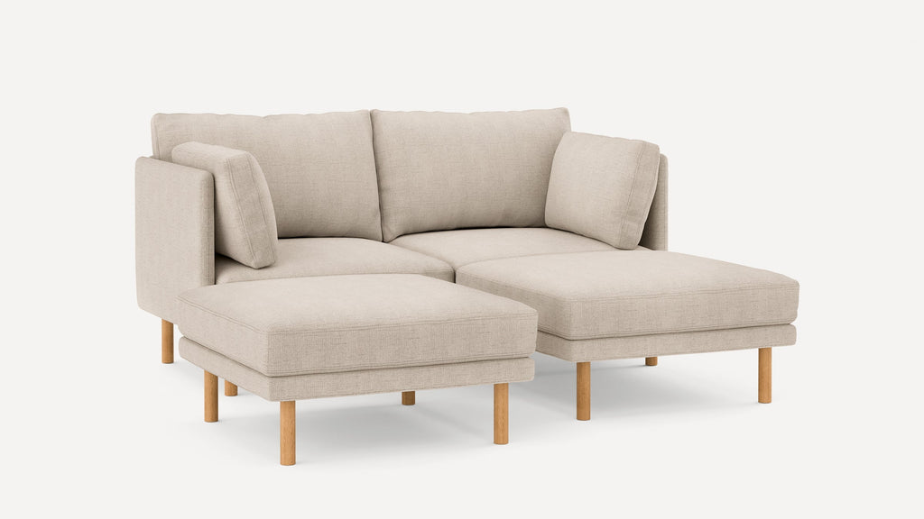 Beige L-shaped sectional sofa with wooden legs, plush cushions, and a modern minimalist design against a plain white background.