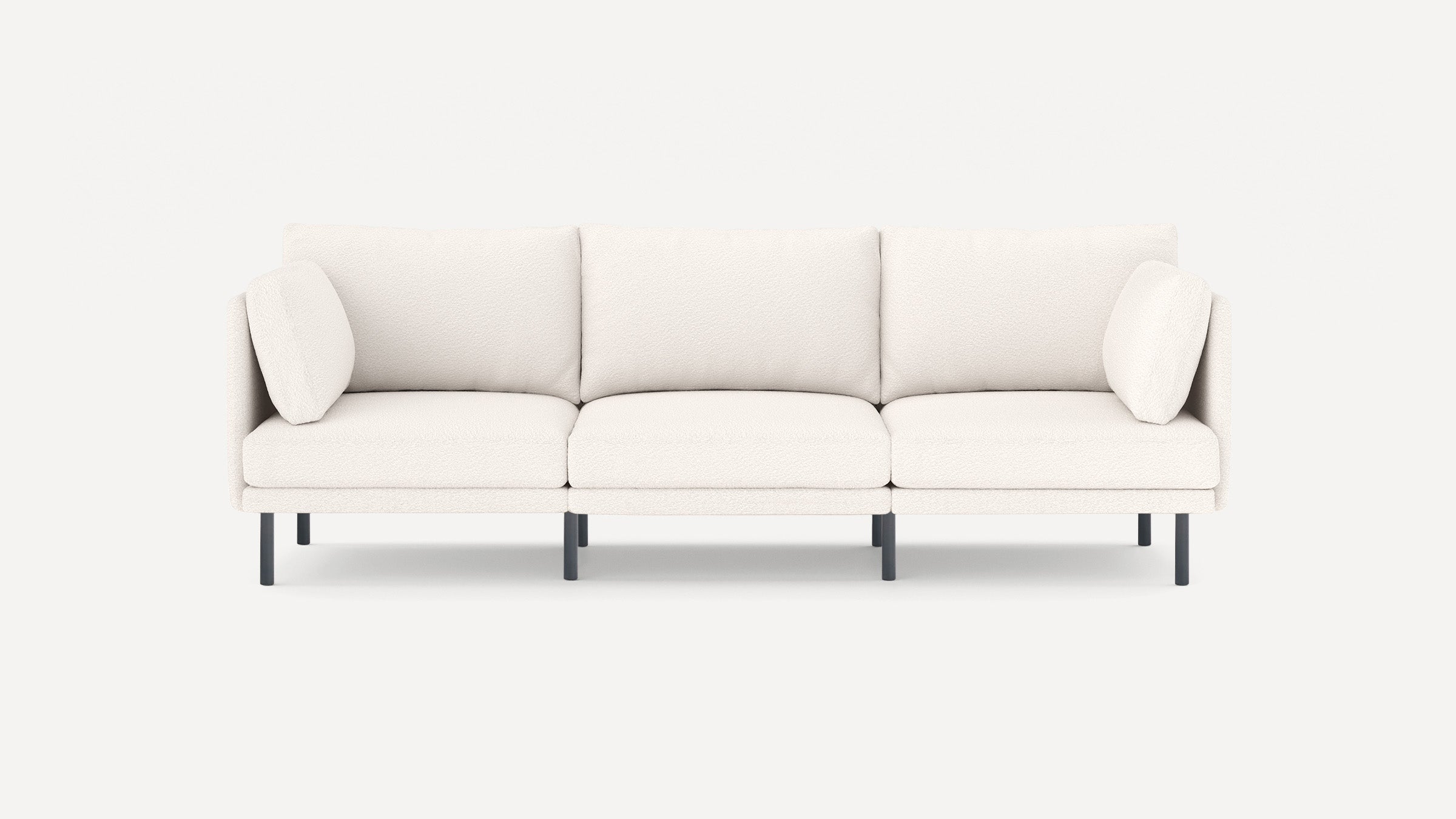 Modern three-seater sofa with white textured upholstery, slim black metal legs, and matching side pillows on each end.