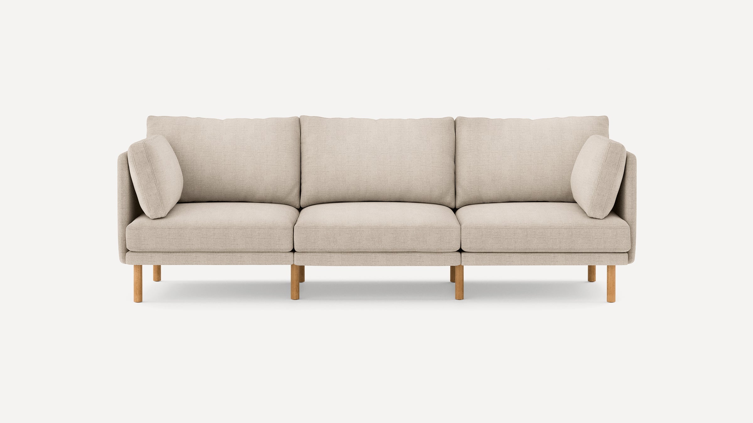 Three-seater beige fabric sofa with wooden legs, featuring removable cushions and arm pillows on each side.