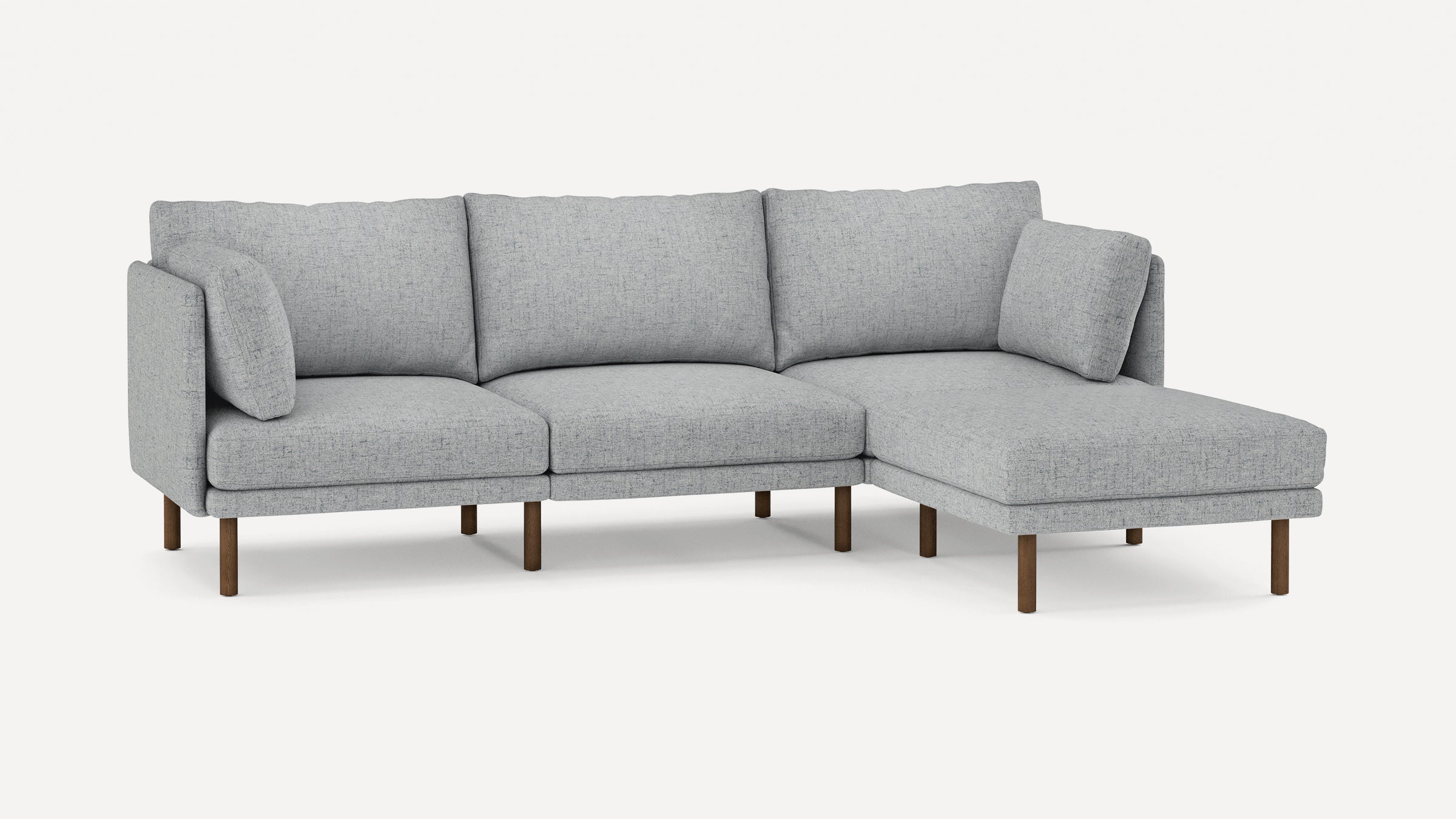 Light gray fabric sectional sofa with wooden legs, featuring three back cushions and an extended chaise lounge on the right side.