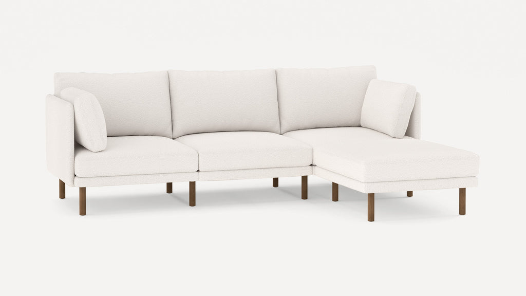 Modern white fabric sectional sofa with wooden legs, including three seat cushions and two matching throw pillows.