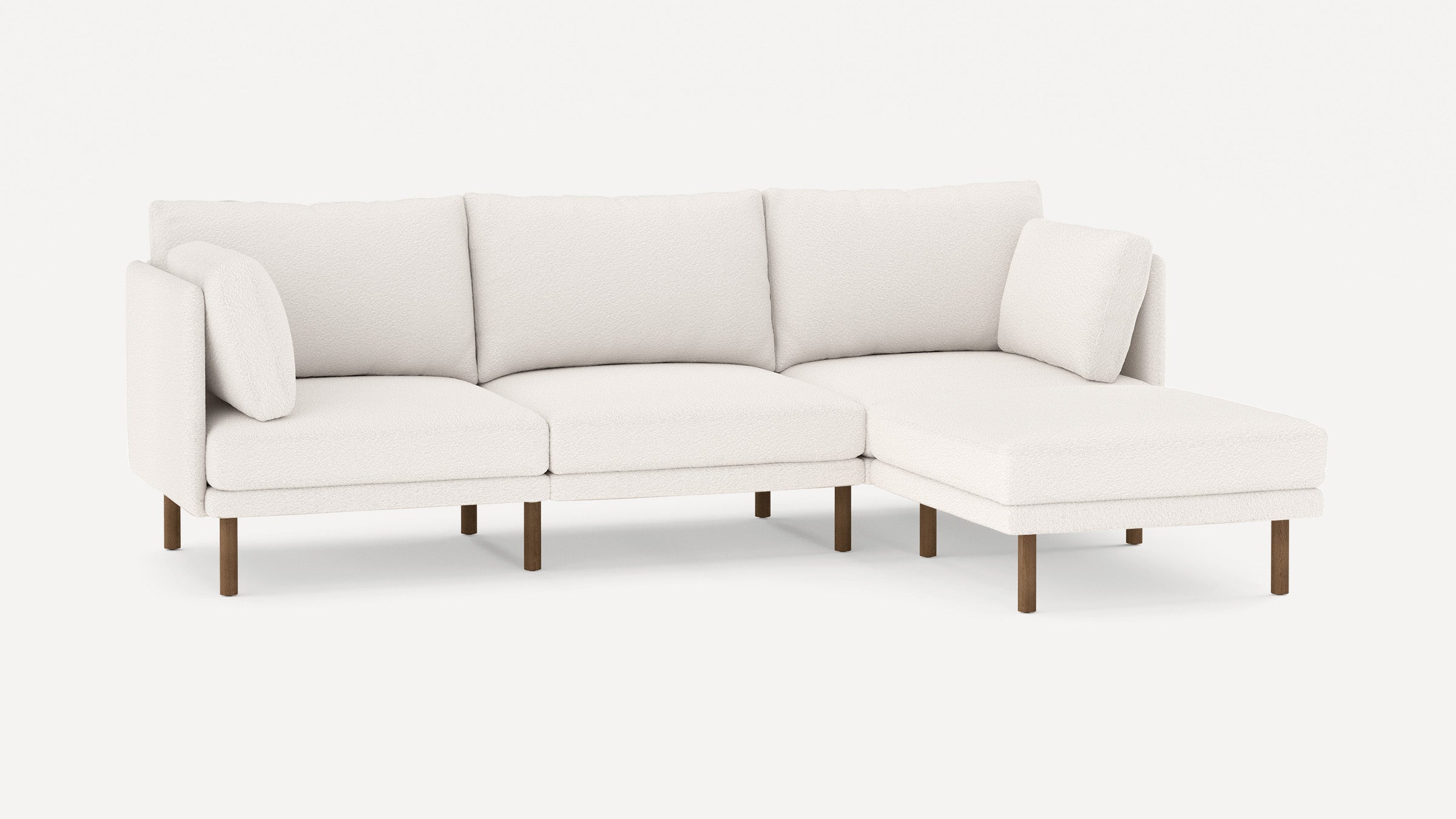 Modern white fabric sectional sofa with wooden legs, including three seat cushions and two matching throw pillows.