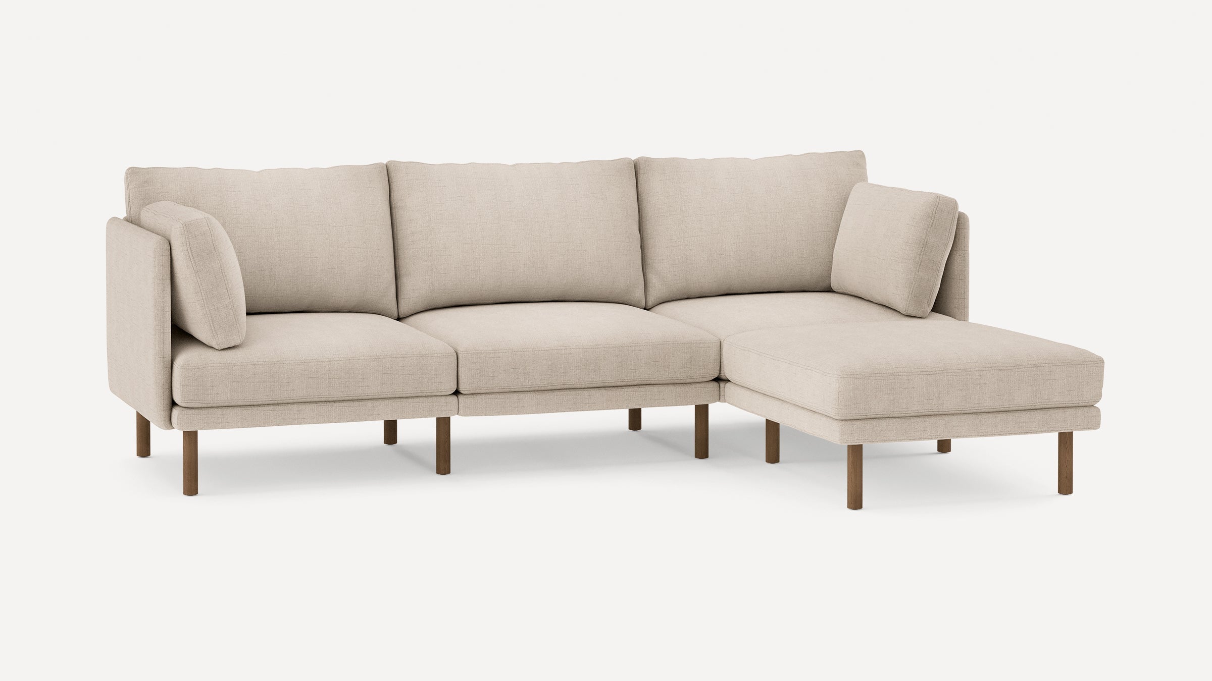Modern beige sectional sofa with wooden legs, featuring three seat cushions and two armrest pillows on a white background.