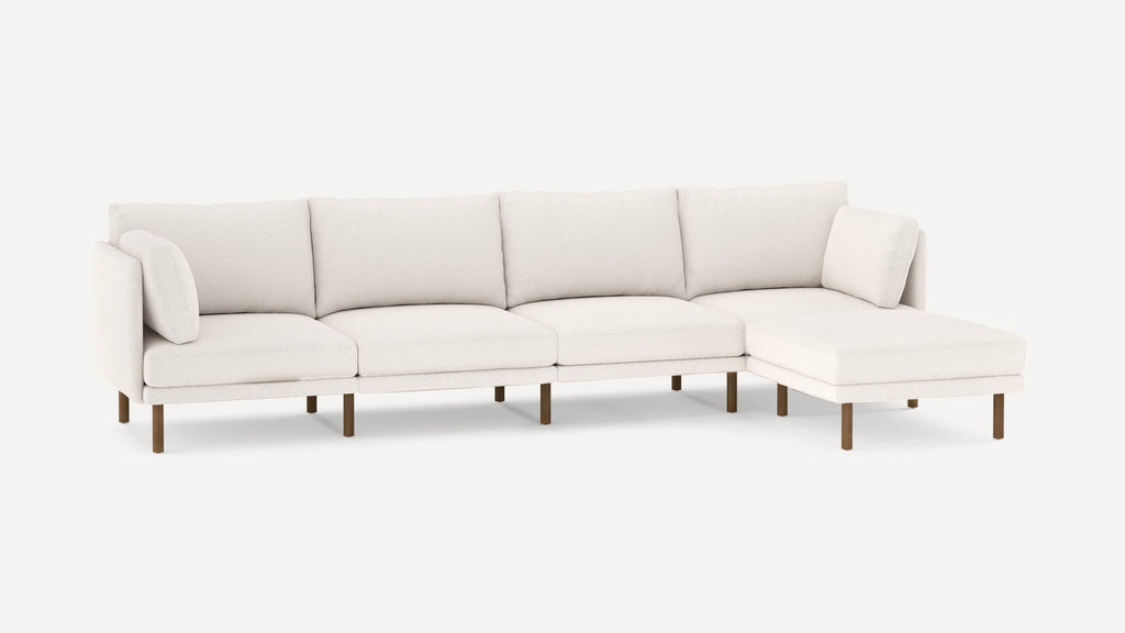 Modern white sectional sofa with plush cushions and wooden legs, featuring a right chaise lounge and two accent pillows.