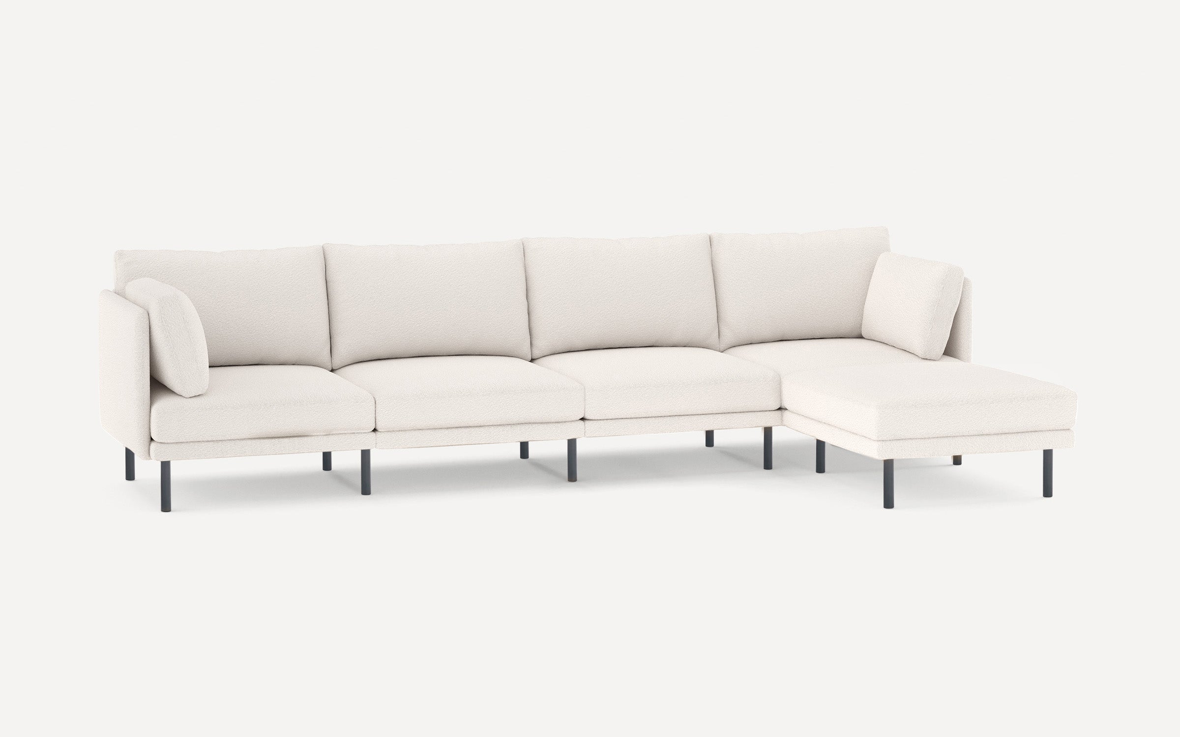 Modern white sectional sofa with four seat cushions, two armrest pillows, and slim black legs on a plain background.