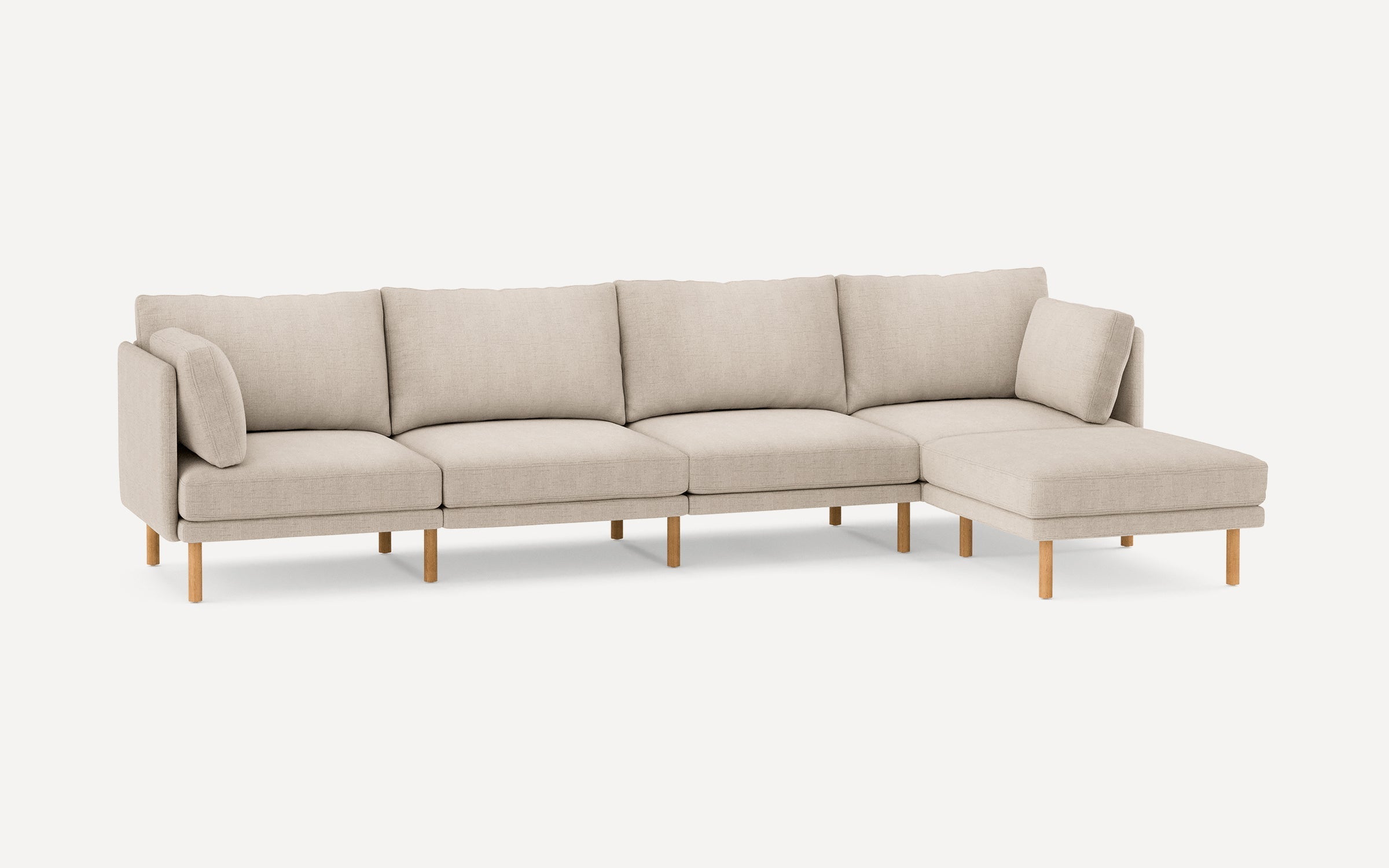 Modern light beige fabric sectional sofa with wooden legs, featuring four seats and a chaise lounge on the right side.