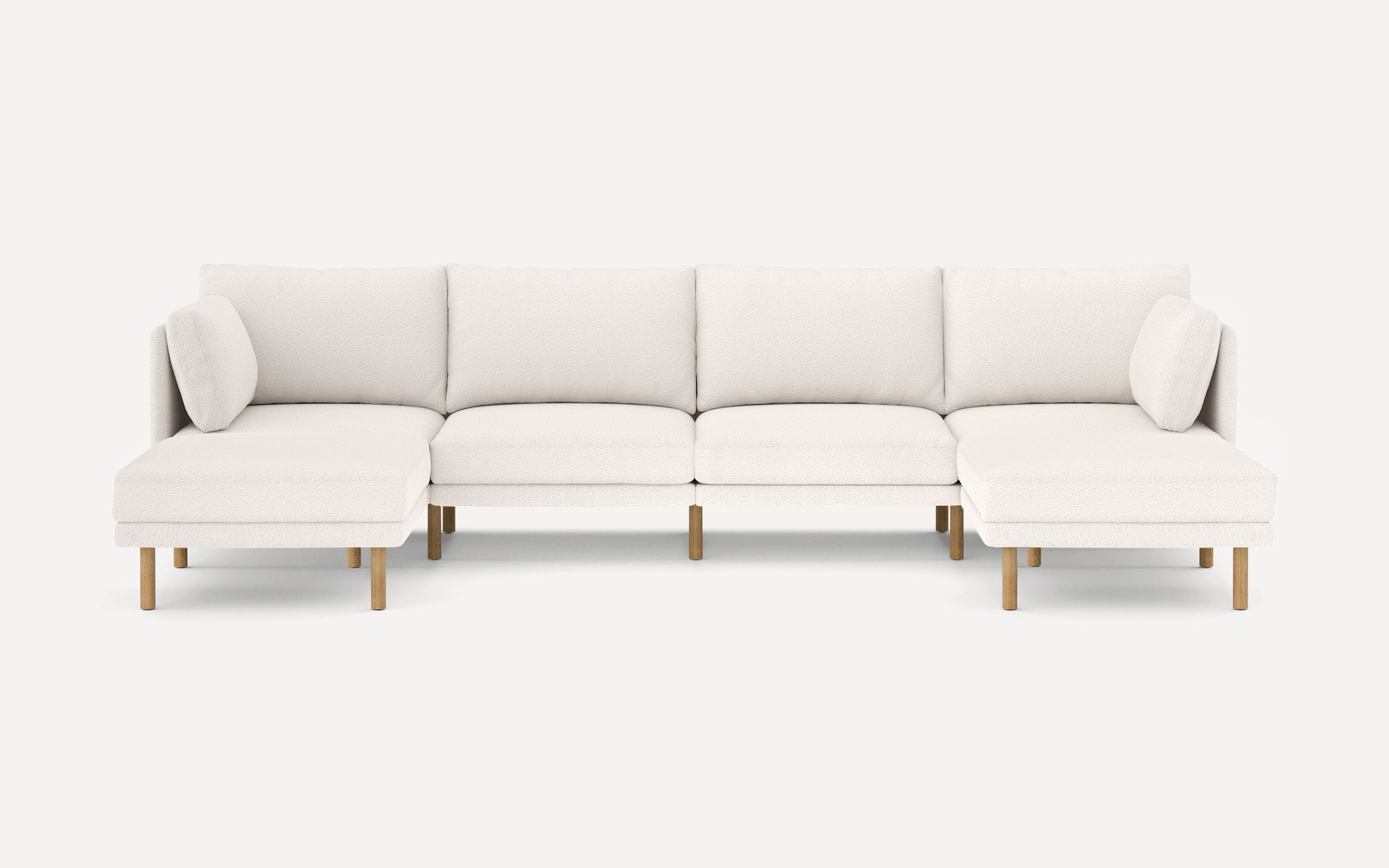 Modern sectional sofa with white textured upholstery, wooden legs, two corner cushions, and extended chaise lounges on both ends.