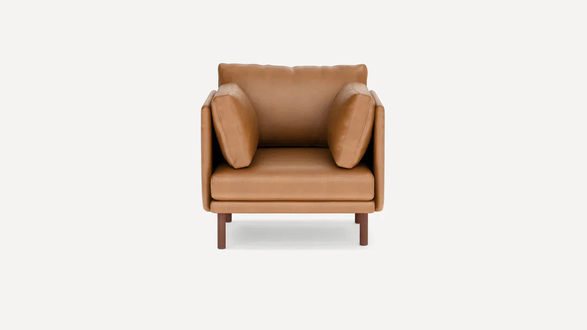 modern tan leather armchair with wooden legs and a cushion on the backrest