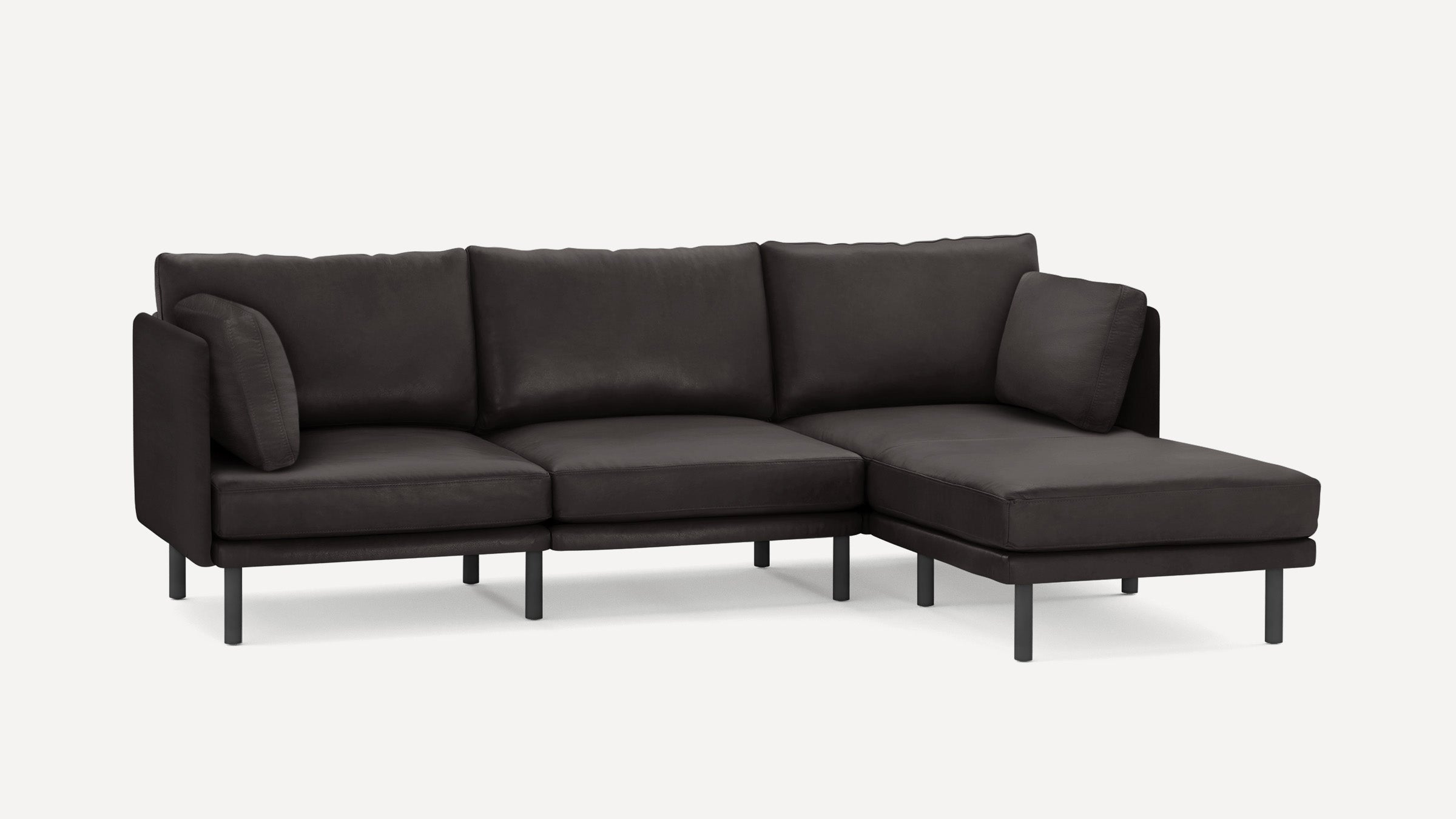 Modern black sectional sofa with minimalist design, metal legs, and plush cushions, featuring a chaise lounge on the right side.