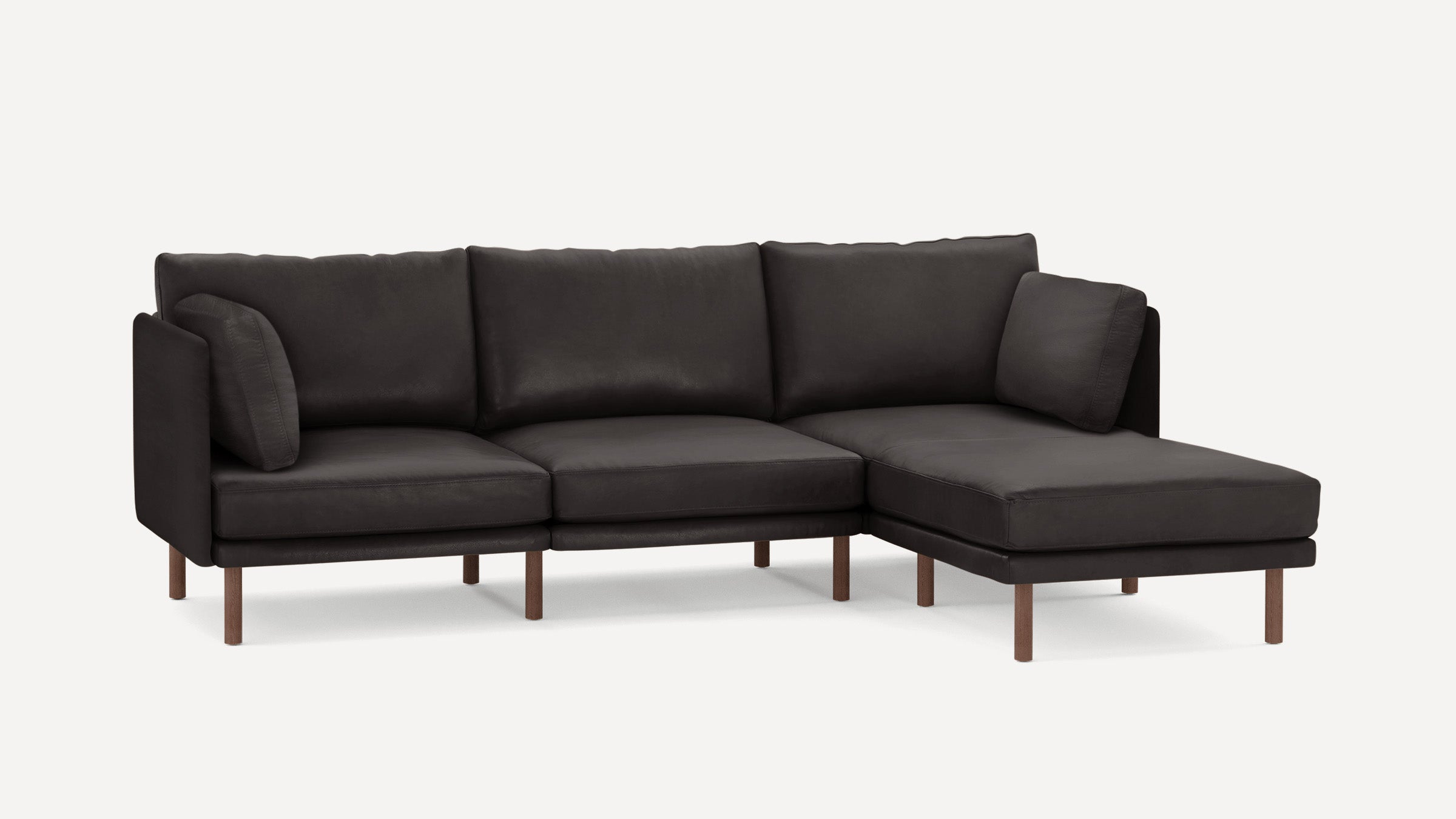 Dark brown leather sectional sofa with wooden legs, featuring three seat cushions and two matching side cushions.