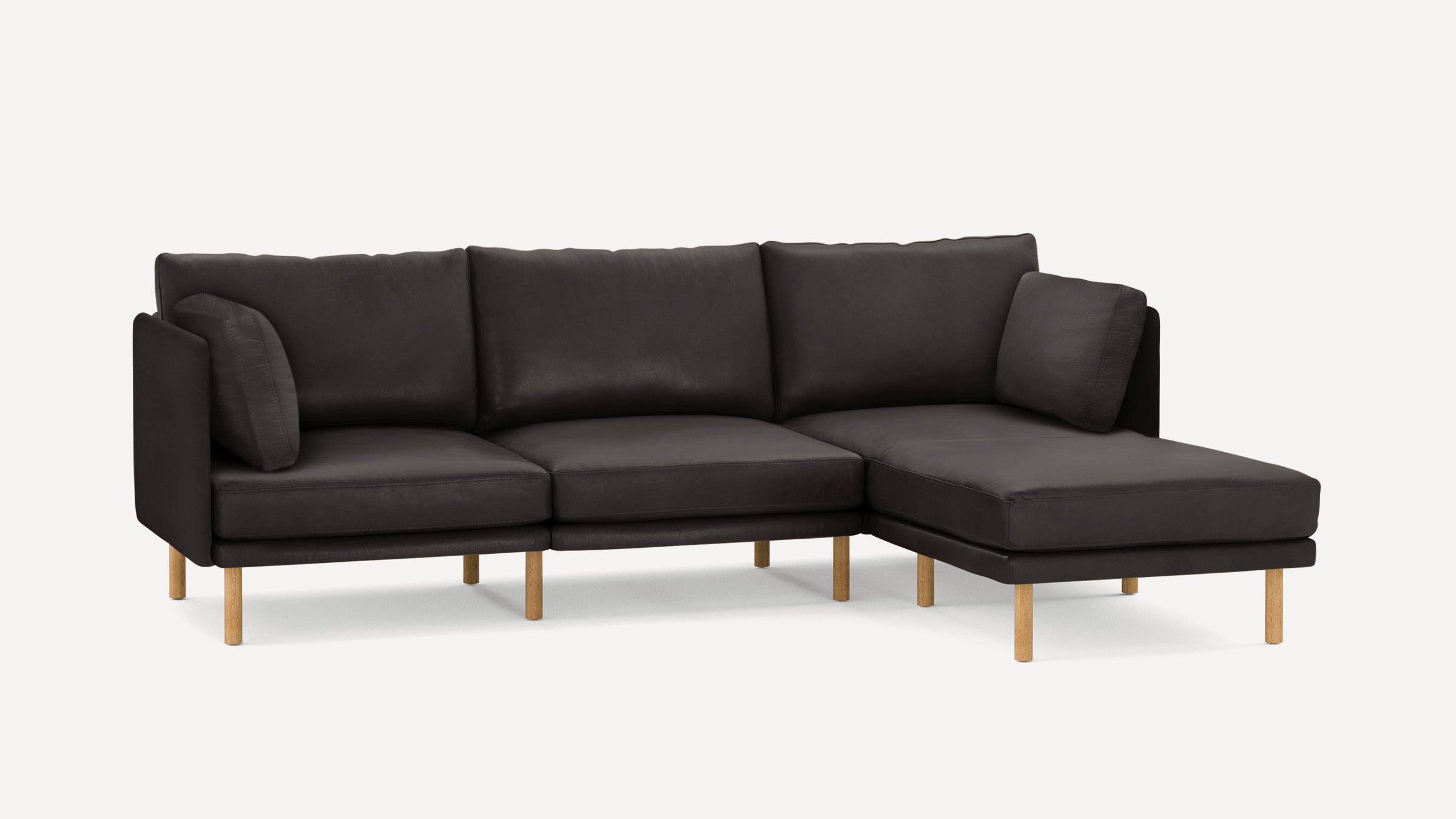 Modern black sectional sofa with wooden legs and plush cushions, including a chaise lounge on the right side.