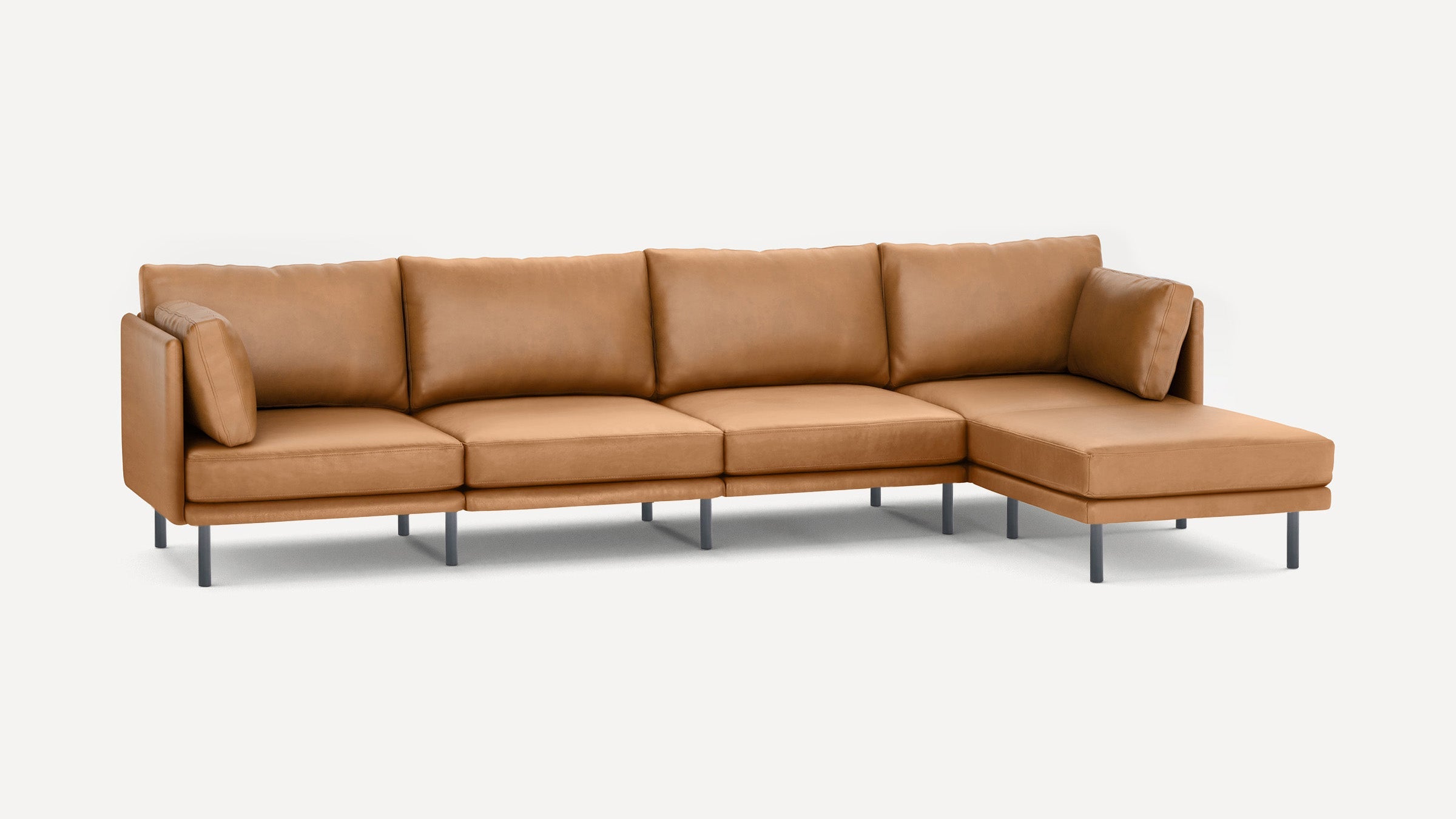 Modern L-shaped sectional sofa in tan leather with slim black metal legs and plush back and side cushions.