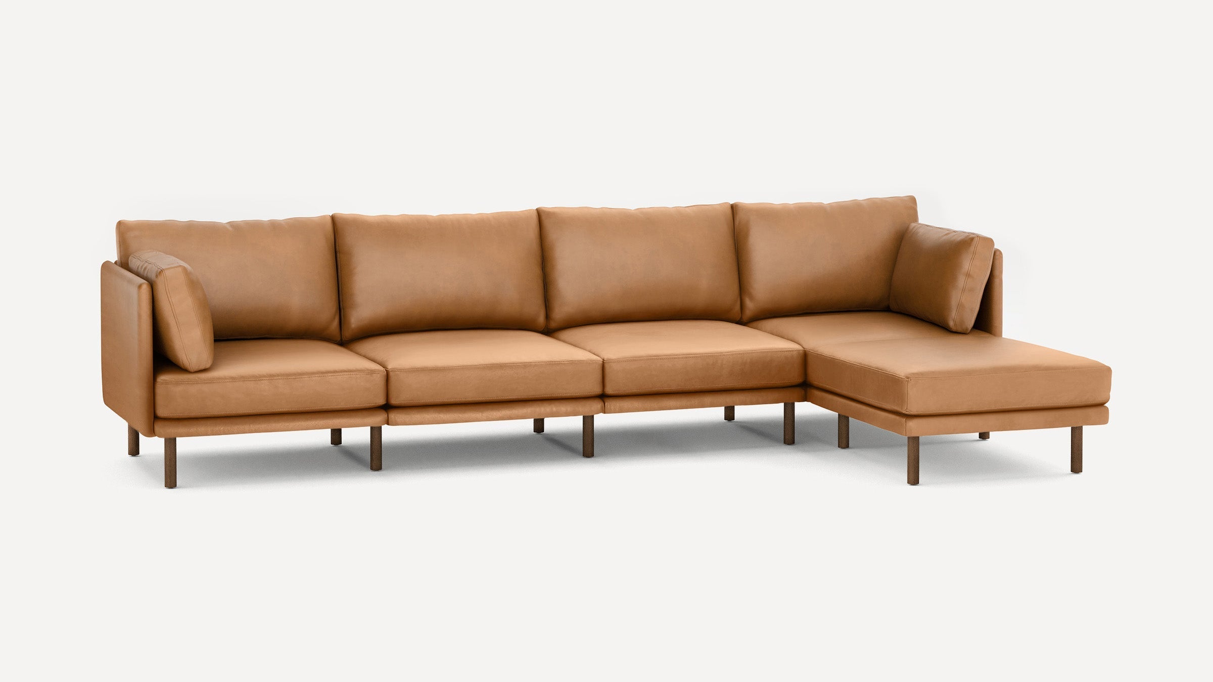 Modern sectional sofa in tan leather with five seat cushions, a chaise on the right, and wooden legs on a white background.