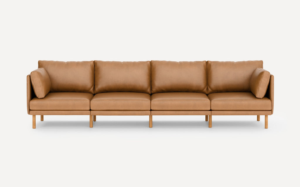 Modern four-seater tan leather sofa with wooden legs and removable cushions, minimalist design on white background.