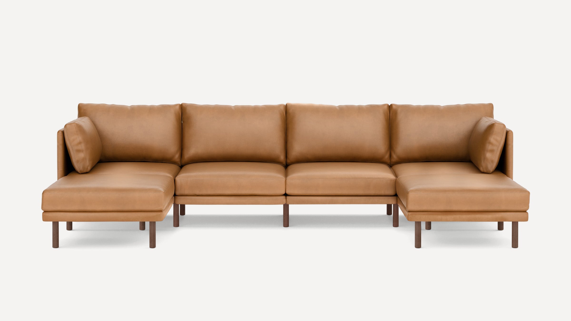 Modern U-shaped sectional sofa in tan leather with wooden legs and matching back cushions on each end.