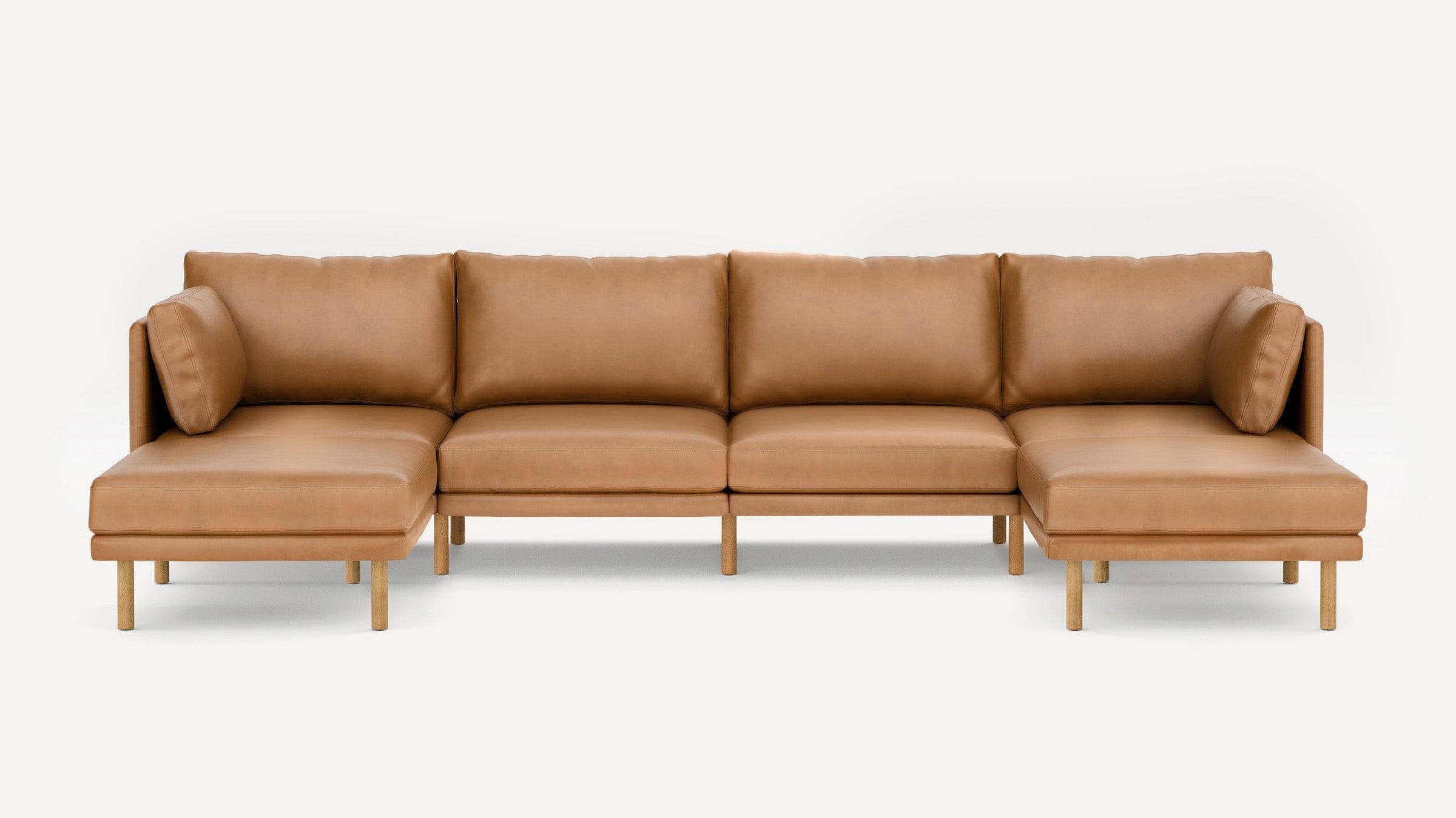 Modern tan leather sectional sofa with wooden legs, featuring left and right chaise lounges and cushioned backrests.